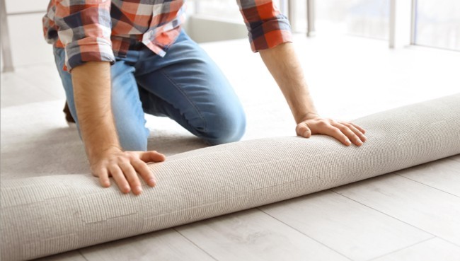 Man rolling carpet for installation | Montgomery's CarpetsPlus COLORTILE